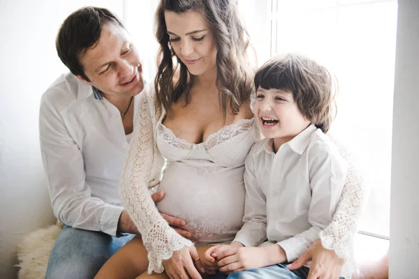 Une famille heureuse attend un deuxième enfant. Femme enceinte avec mari et petit garçon. Joyeux famille sur fond blanc. Deuxième grossesse, concept de maternité . — Photo