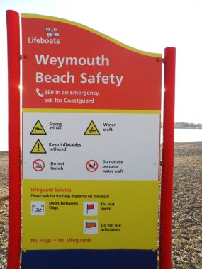 Halk Plajı Emanet işaretiyle bilgi ve uyarı simgeleri, Weymouth, Dorset, İngiltere'de sahilde üzerinde gerçekleştirilen