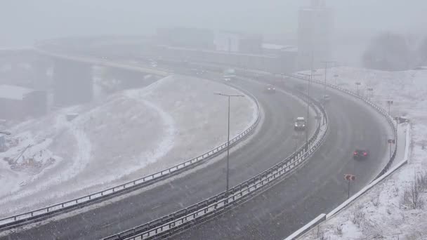 Автомобили едут по снежной дороге зимой, движение по шоссе в снегопад, метель — стоковое видео