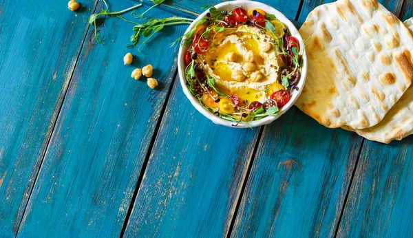 Hummus met olijfolie, spruiten en tomaten Stockfoto