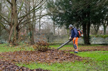 Soest, Almanya - 18 Aralık 2017: Yaprakları park adam elektrikli süpürge ile temizlik.