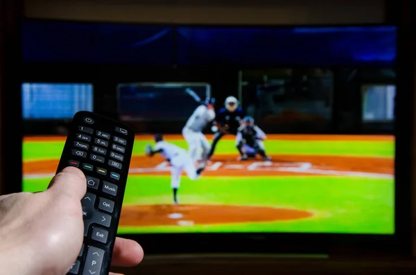 Man watching baseball on TV and using remote controller.