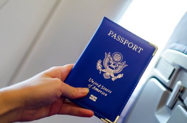 Uçak kabiniçinde el tutarak ABD pasaportu.