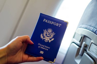 Uçak kabiniçinde el tutarak ABD pasaportu.