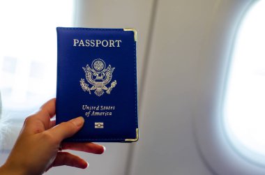 Uçak kabiniçinde el tutarak ABD pasaportu.