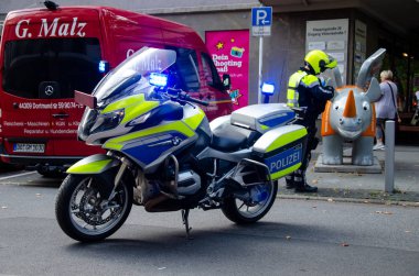 Dortmund, Almanya - 2 Ağustos 2019: Sokaklarda devriye gezen motosikletin yakınında polis.
