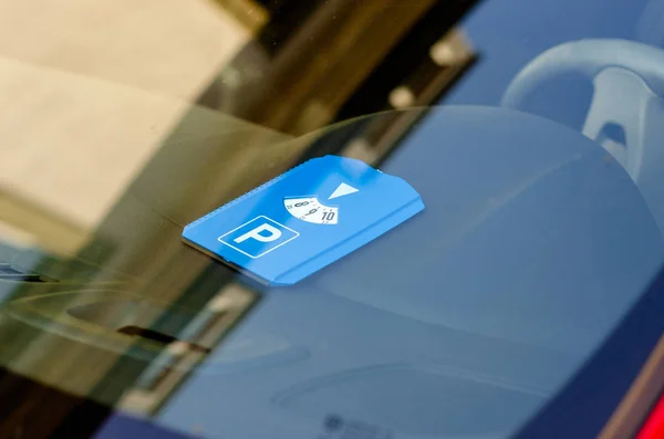 Дискова парковка це система, що дозволяє безкоштовну парковку, обмежену часом, через відображення паркувального диска або годинникового диска, що показує час припаркування транспортного засобу . — стокове фото