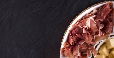 Bira atıştırmalıkları ve tapas: peynir, koyu arka planda beyaz plaka üzerinde Jamon. Yiyecek ve içecekler