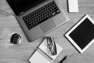 Masadaki gereçler ve aygıtlar: pc, bilgisayar, kalem, not defteri, tuş takımı, kalem, defter, fare. Üst Manzara. Çeşitli aletler ve ofis malzemeleriyle dolu bir masa. Düz taban. Yüksek açı görünümü. 