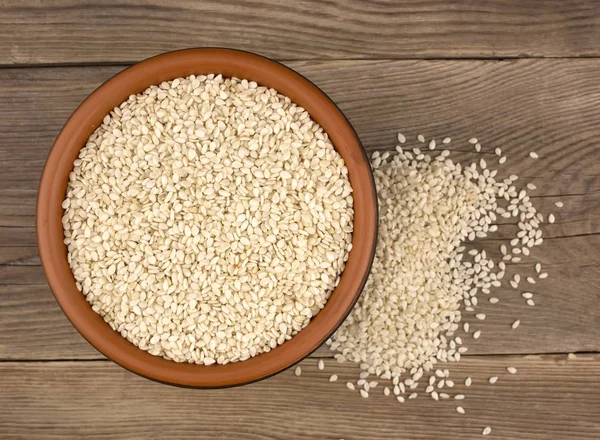 Bir kase bir tahta kaşıkla ahşap arka plan üzerinde beyaz susam