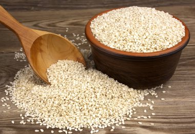 Bir kase bir tahta kaşıkla ahşap arka plan üzerinde beyaz susam