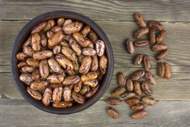 Ahşap masa üzerinde seramik kase kuru fasulye. Üstten görünüm