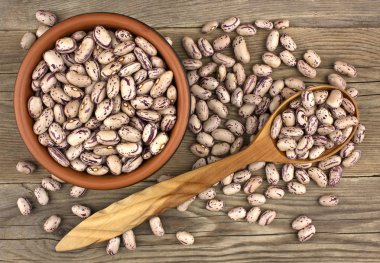 Tahta kaşıkla ahşap masa üzerinde seramik kase kuru fasulye. Üstten görünüm