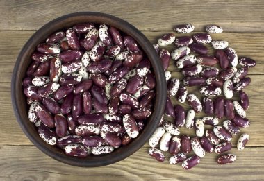 Ahşap masa üzerinde seramik kase kuru fasulye. Üstten görünüm