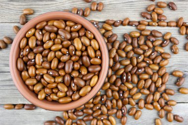 Ahşap masa üzerinde seramik kase kuru fasulye. Üstten görünüm