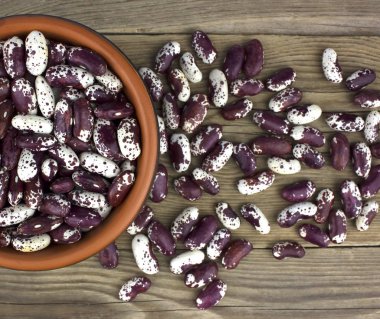 Ahşap masa üzerinde seramik kase kuru fasulye. Üstten görünüm