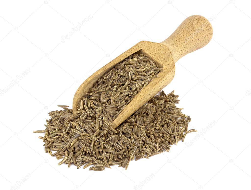 Food ingredients: heap of cumin in a wooden scoop, on white background