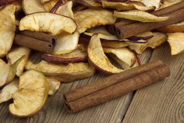 Ev yapımı kurutulmuş organik elma dilimleri, taze elma ve tarçın ile eski bir ahşap masa.