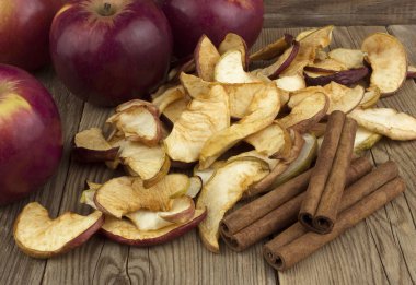 Ev yapımı kurutulmuş organik elma dilimleri, taze elma ve tarçın ile eski bir ahşap masa.