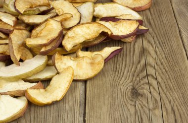 Ev yapımı kurutulmuş organik elma dilimleri, eski bir ahşap masa. Arka plan elma kurutulmuş. 