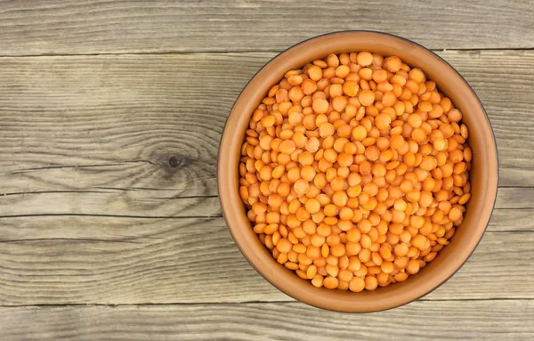 Red lentils in plate on wooden background — Stock Photo, Image