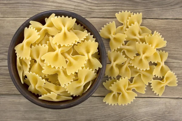 Massa farfalle crua na tigela na mesa — Fotografia de Stock