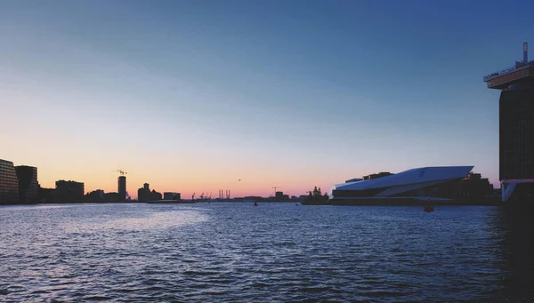 Rzeka trenerem port w Amsterdamie w zachód słońca — Zdjęcie stockowe