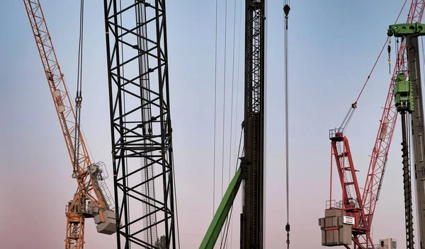 Résumé Fond industriel avec des silhouettes de grues de construction sur un ciel magnifique au coucher du soleil — Photo