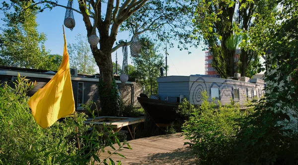 Amsterdam Casas flotantes a orillas del río Amstel con coloridas banderas de fiesta y sol —  Fotos de Stock