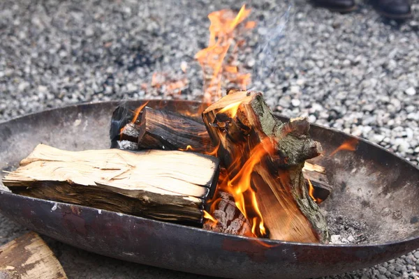 Çakıl bir zeminüzerinde metal yangın kase kamp ateşi yanan ahşap — Stok fotoğraf