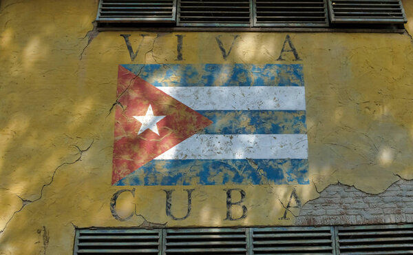 Кубинский флаг на желтой стене с окнами
