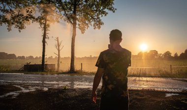 Gün batımında mısır tarlasını sulayan tarımsal sulama sisteminin silueti. Ortadaki pivot fıskiye sistemini kullanarak mısır tarlası sulama