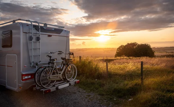 Автономний кемпер RV з велосипедами паркування в красивому райському місці на пагорбі з заходом сонця і дивовижним видом Стокове Фото