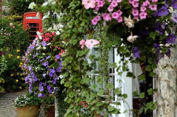 red telephone booth with flowers on the wall in england