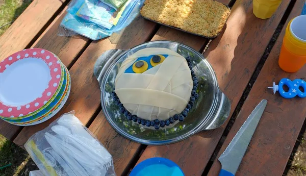 cake in the form of a mummy face for a birthday with plates and cutlery