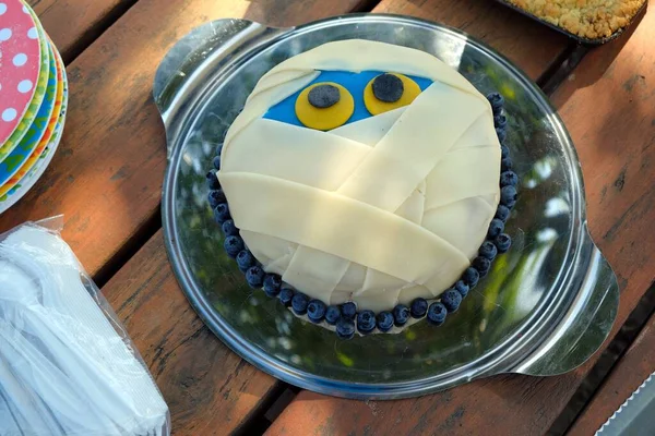 cake in the form of a mummy face for a birthday with plates and cutlery