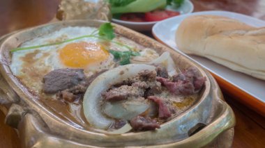 tavada kızartılmış sığır eti sıcak tavada kızarmış yumurta ile servis soğan ile Asya Kahvaltı