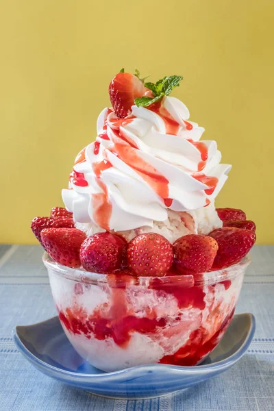 Bingsu - Korean shaved ice dessert with sweet toppings with strawberry and whipping cream
