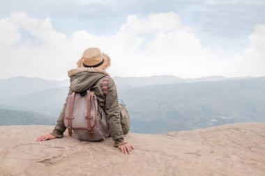Hippi kız kayalık bir gökyüzü mavi karşı dağın zirvesine oturan sırt çantası ile