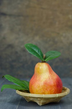 Olgun kırmızı armut sepeti ahşap masa üzerinde üzerinde yeşil yaprakları ile