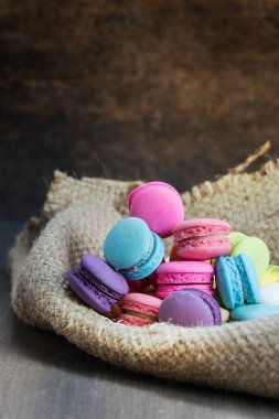renkli macarons ahşap masa üzerinde bir çuval üzerinde