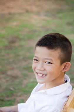 Yeşil bahçe içinde gülümseyen mutlu Asya çocuğun yakın çekim