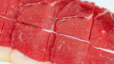 Beyaz arka planda bir tabakta çiğ sığır etinin üst görünümü