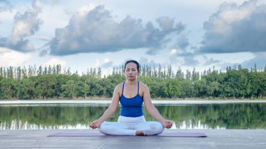 Asyalı kadın pratik yoga poz, güzel göl - manzaralı açık havada egzersiz dinlenmek doğa