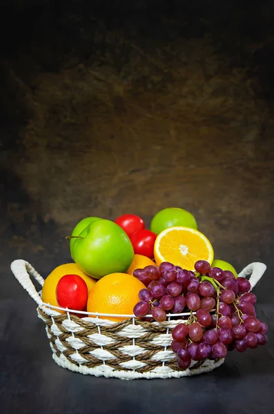 fresh vegetables and fruits in wicker basket over wooden background