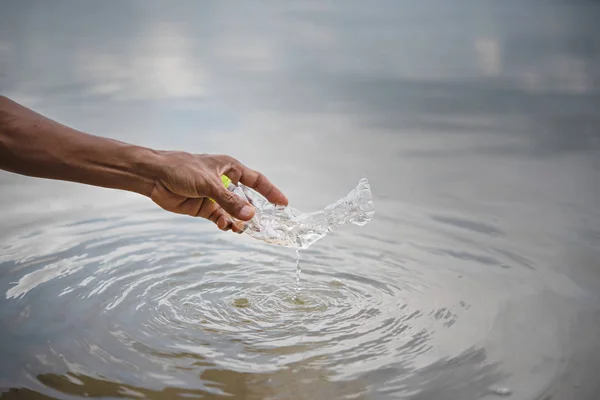 hand pick up plastic bottle from water