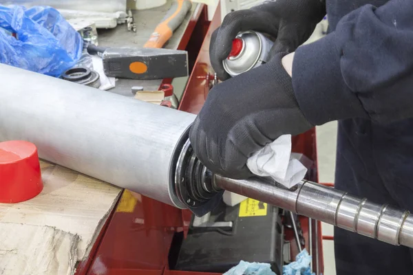 mechanic cleans large metal cylinder, close up