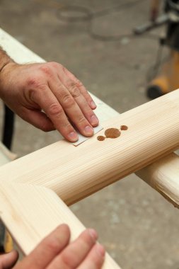 Marangoz atölyedeki ahşap pencereyi zımparalıyor, kapat.
