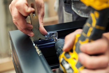 Metal parçaları ahşap pencerelere elle yerleştirip, kapatıyorlar.