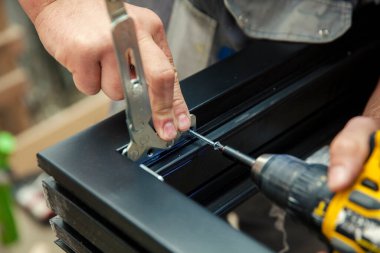 Metal parçaları ahşap pencerelere elle yerleştirip, kapatıyorlar.